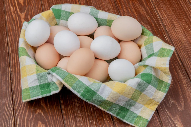 top-view-multiple-fresh-chicken-eggs-yellow-green-checked-tablecloth-wooden-background_141793-15030